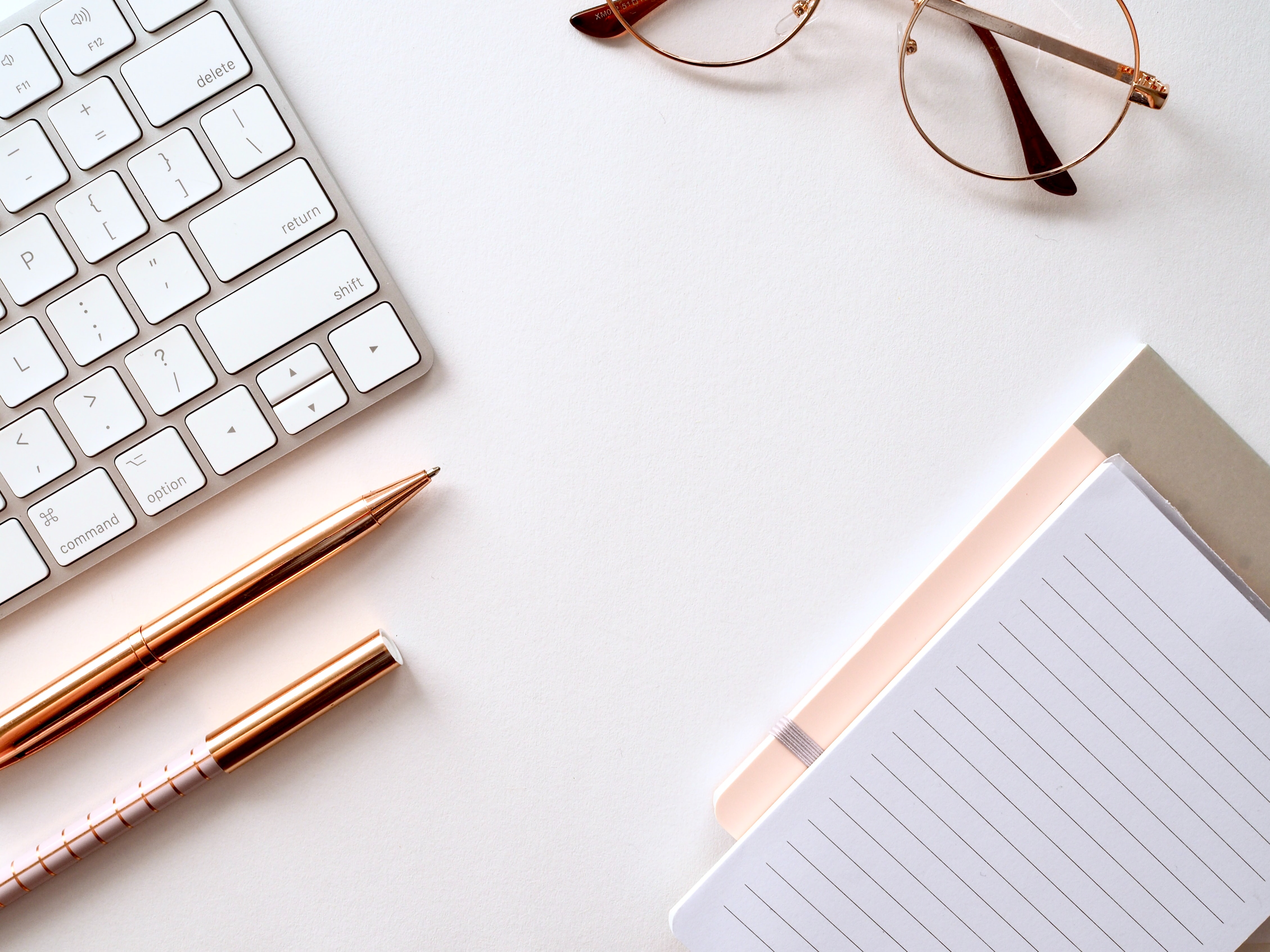 keyboard, eye glasses and writing materials on plain background